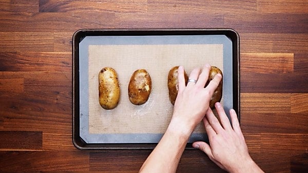 potatoes on baking sheet being rubbed with oil