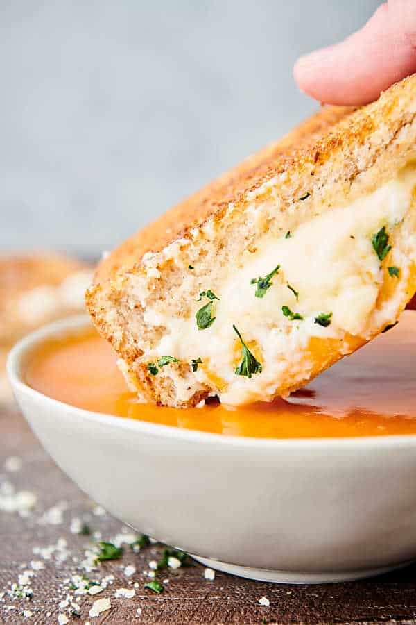 grilled cheese sandwich being dipped into tomato soup
