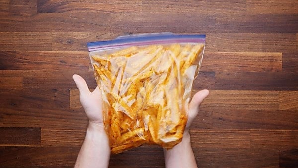 potato slices being mixed with seasonings in ziplock bag