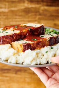 plate of chicken meatloaf on mashed potatoes held