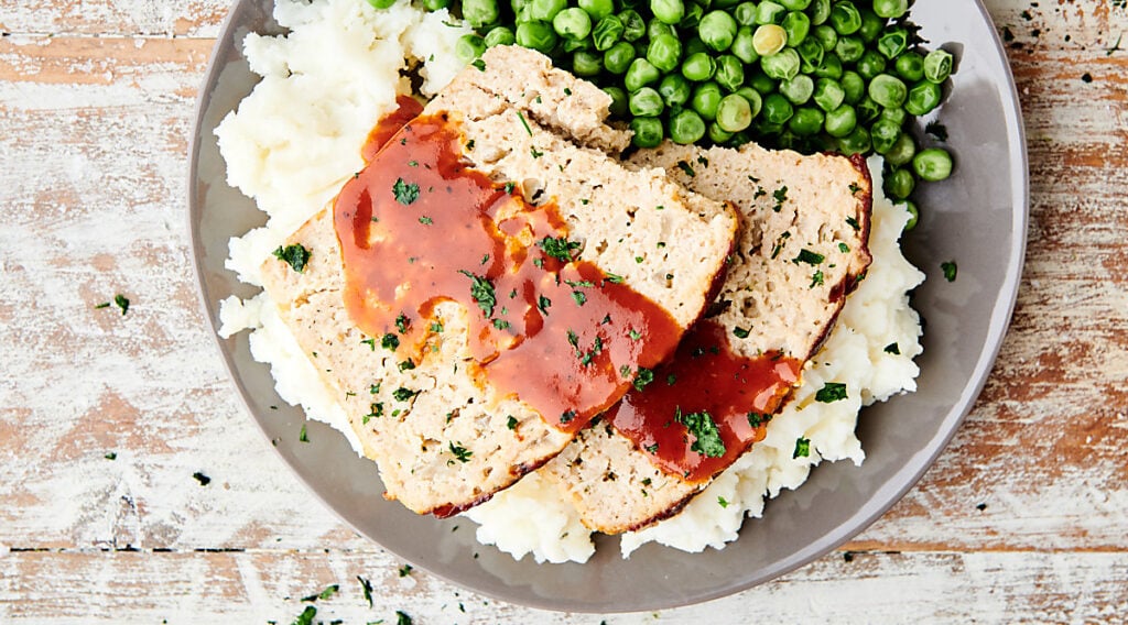 chicken meatloaf on plate with mashed potatoes and peas above