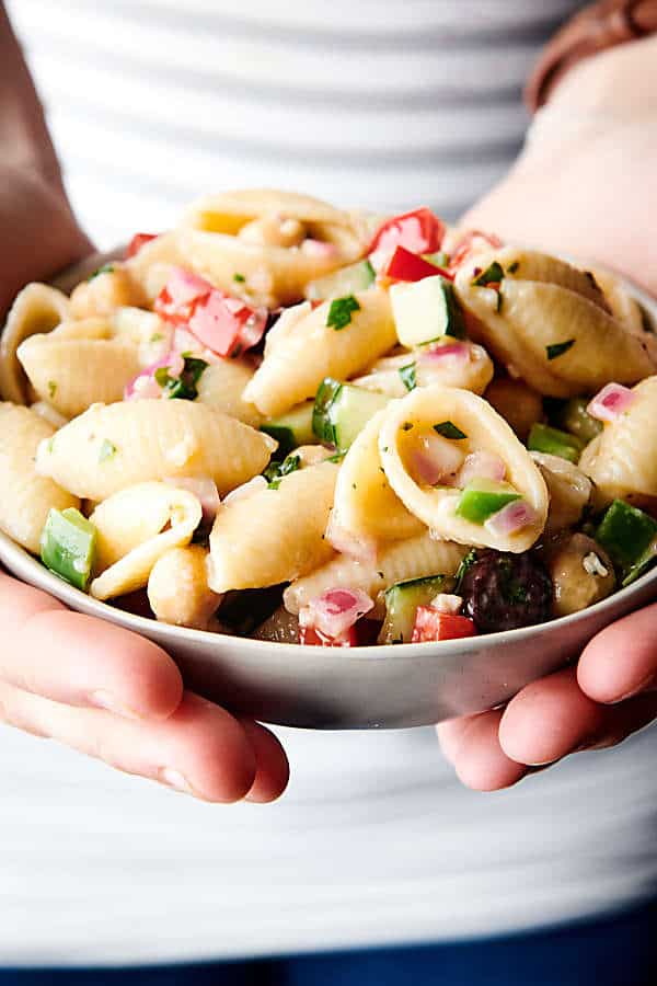 bowl of vegan pasta salad held two hands