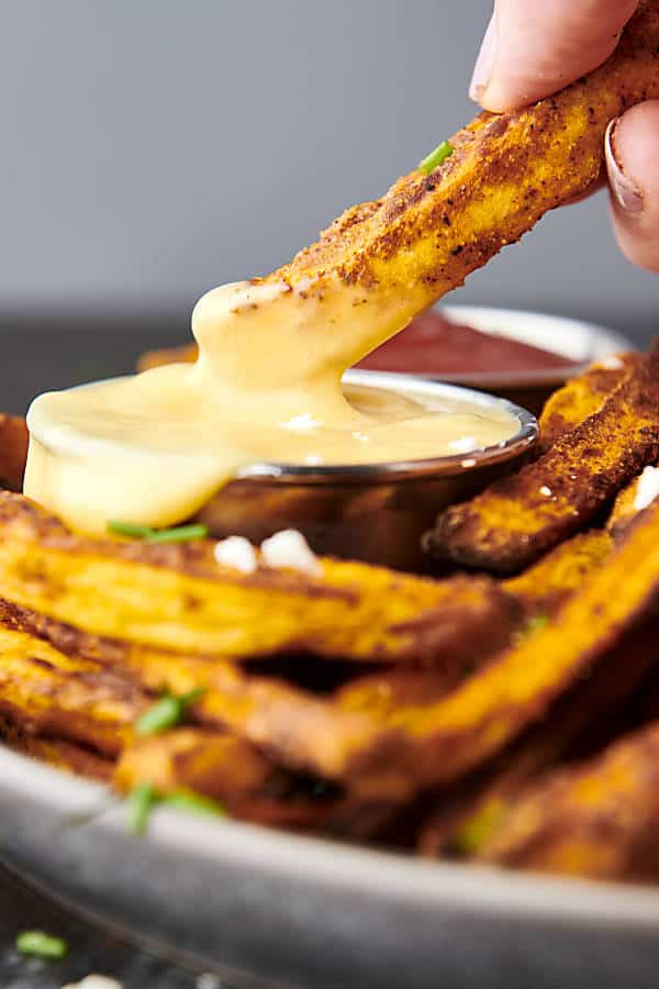 air fryer sweet potato fries being dunked into honey mustard