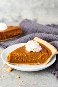 slice of vegan pumpkin pie on a plate with coconut whipped cream