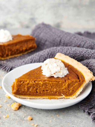 slice of vegan pumpkin pie on a plate with coconut whipped cream