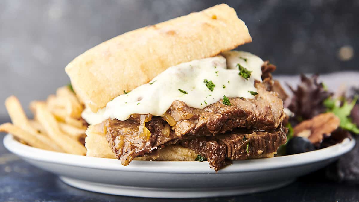plate with instant pot french dip sandwich, salad, and fries