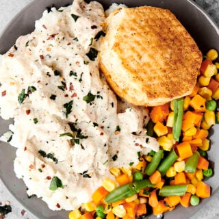 chicken and gravy with potatoes, veggies, and biscuit
