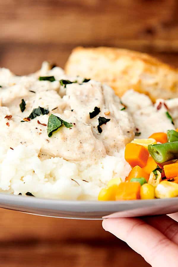 creamy crockpot chicken and gravy on top of mashed potatoes