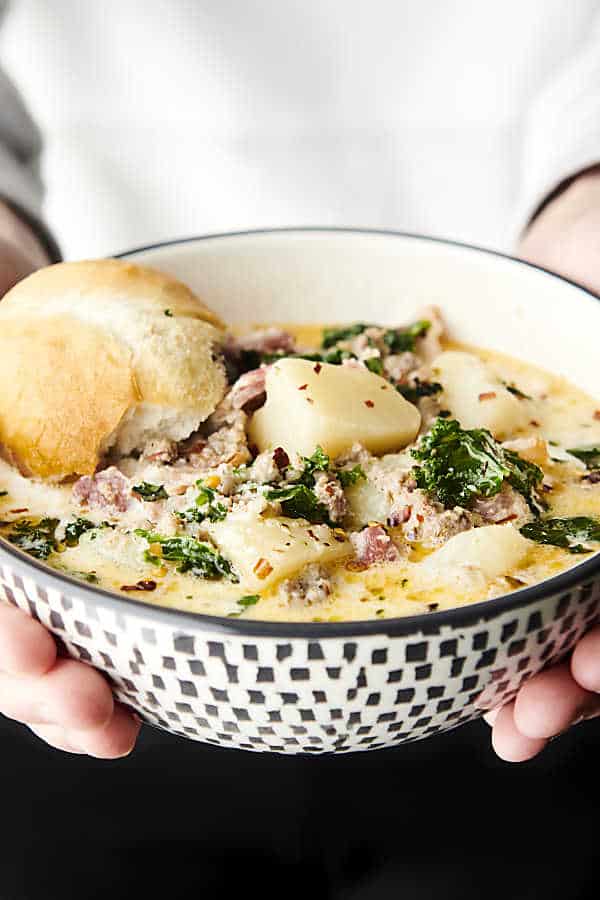 holding a bowl of zuppa toscana