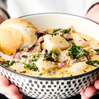 holding a bowl of instant pot zuppa toscana