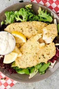 parmesan tilapia on a bed of greens