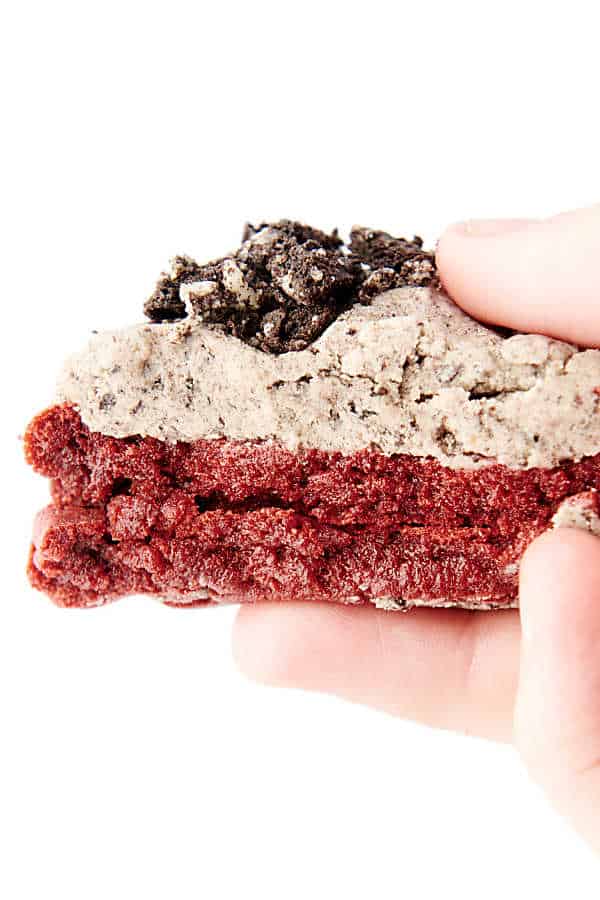 holding a red velvet cookie with oreo frosting