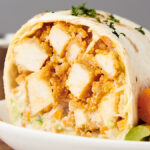 buffalo chicken wrap on a plate with ranch, carrots, and celery