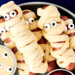 crescent wrapped mummy dogs on a plate with ketchup and mustard