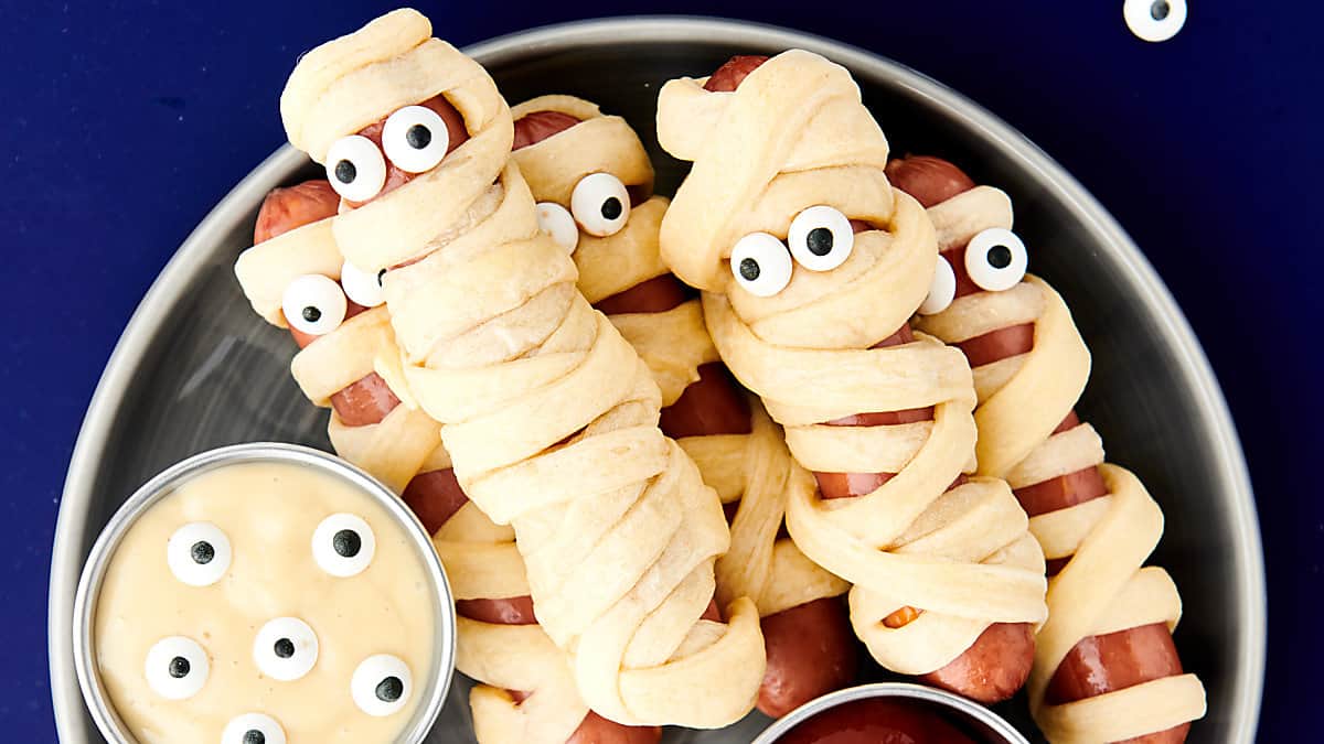 crescent wrapped mummy dogs on a plate with ketchup and mustard
