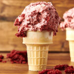 red velvet ice cream with cream cheese frosting swirls in a cone