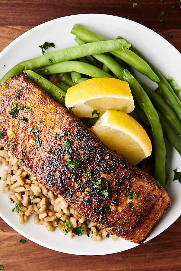 blackened salmon on a plate with rice and green beans