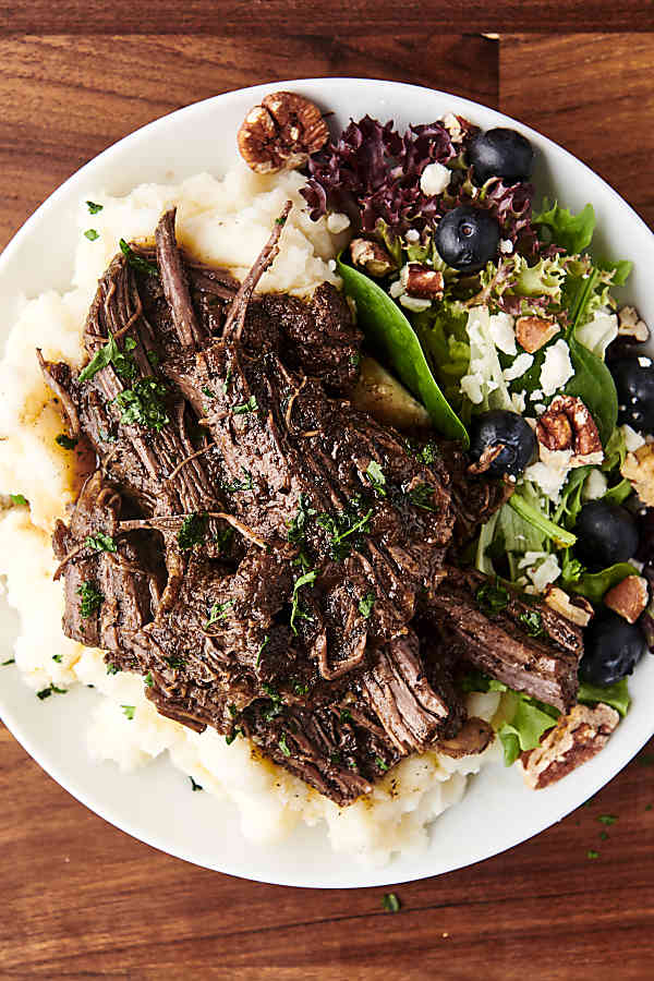 plated slow cooked beef on top of mashed potatoes