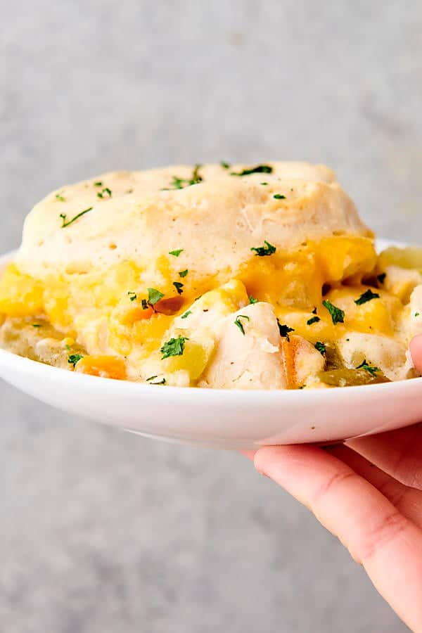 holding a plate with chicken pot pie casserole