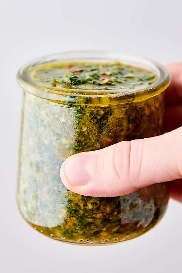 holding a jar of chimichurri sauce