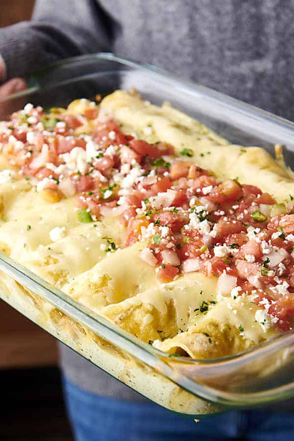 holding a pan of creamy enchiladas suizas