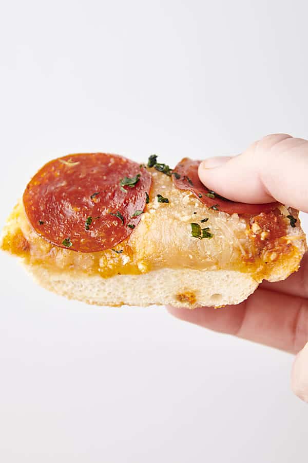 holding a slice of french bread pizza