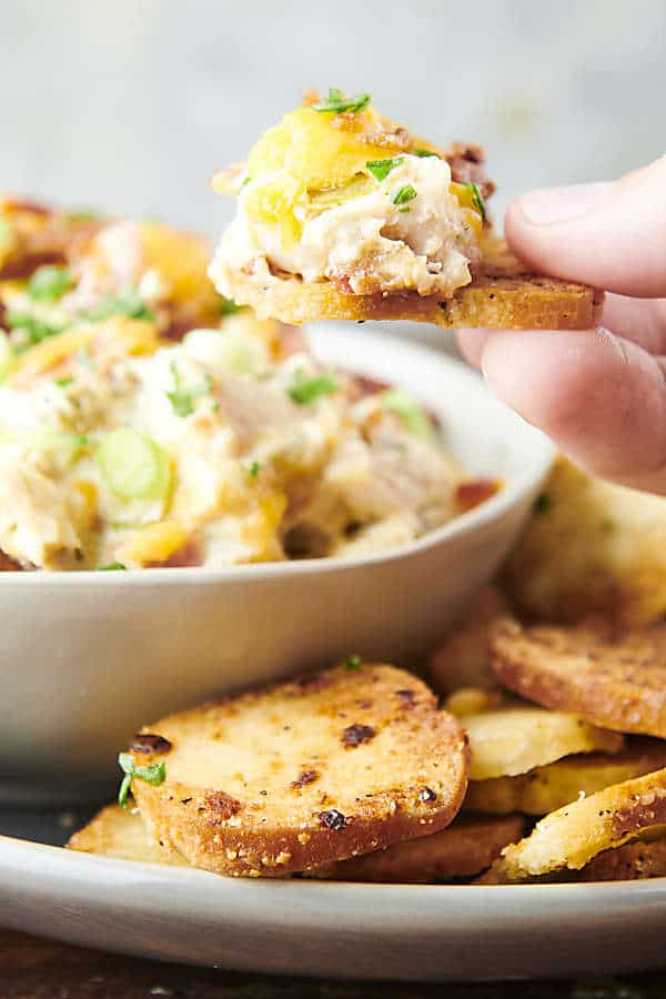 using a bagel chips to dip into chicken bacon dip