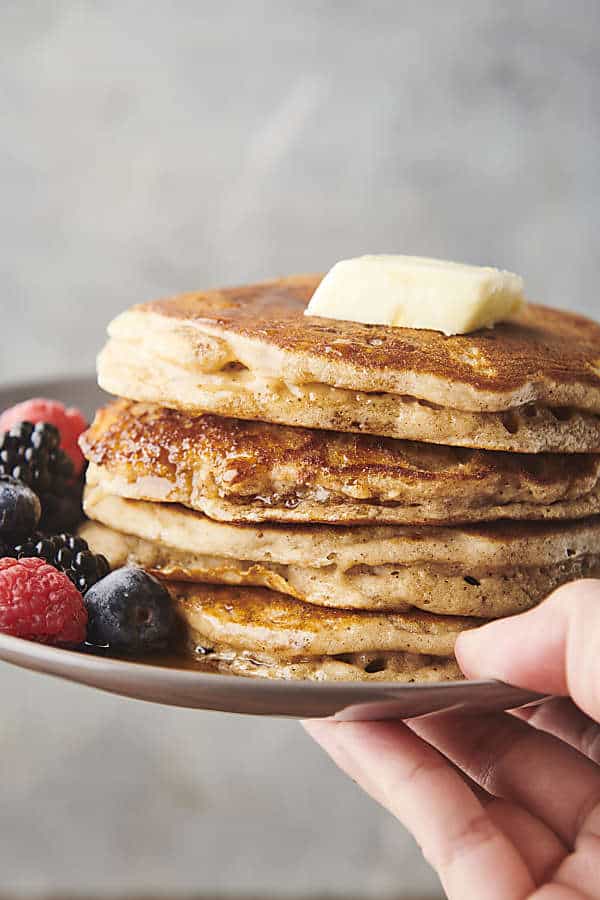 stack of buttermilk pancakes on a plate topped with butter