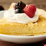 slice of buttermilk pie on a plate topped with whipped cream and fruit