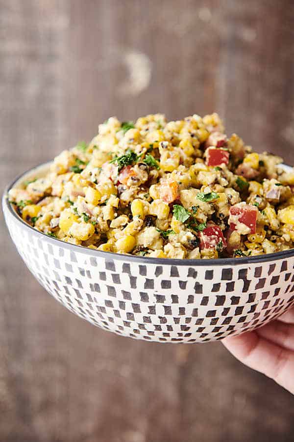 holding a bowl of mexican street corn salad