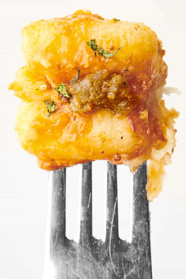 two potato gnocchis on a fork with sausage