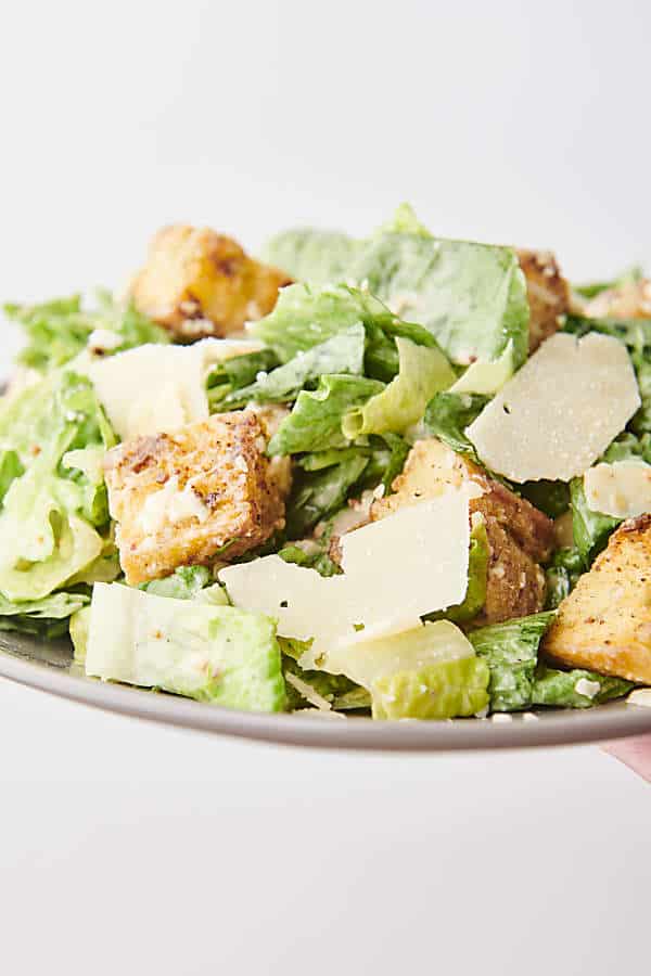 holding a plate of caesar salad