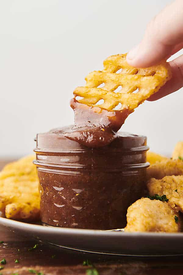 Dunking a waffle fry into homemade BBQ sauce