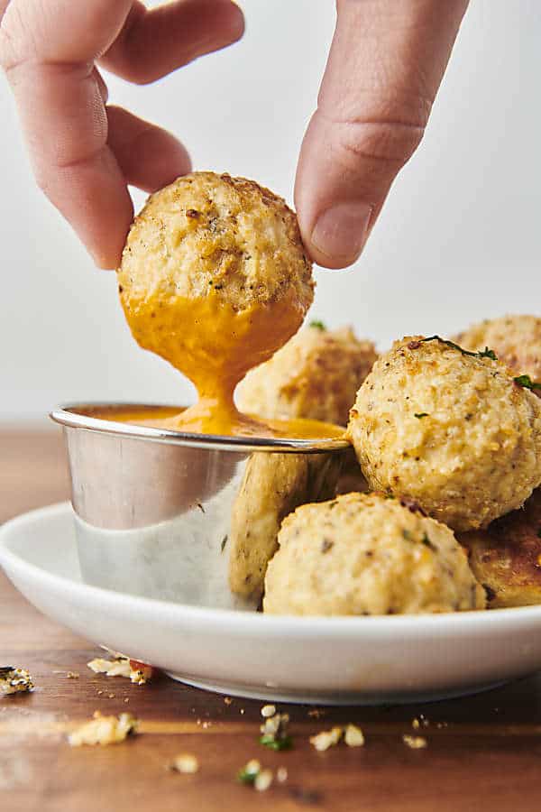 dunking a chicken meatball in sauce