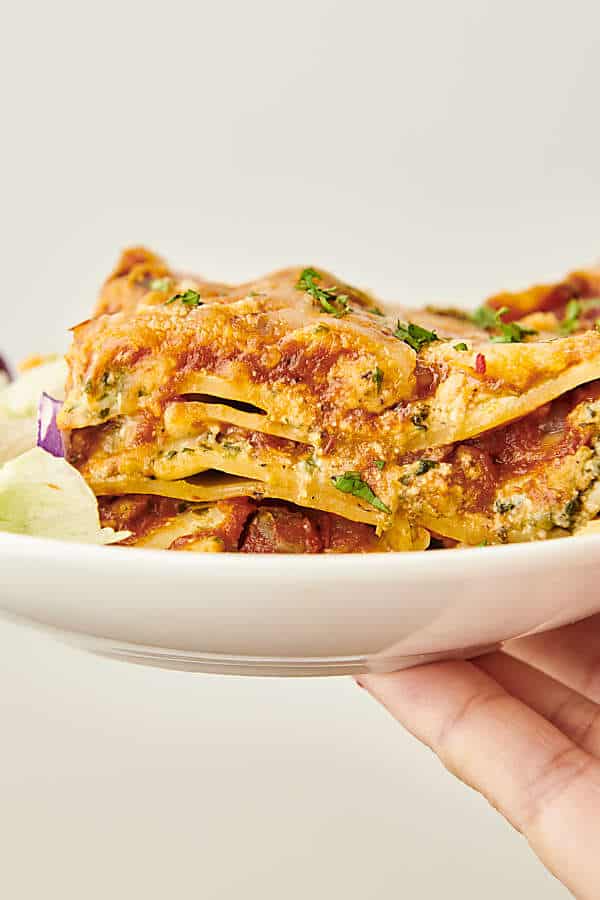 holding a plate of healthy lasagna