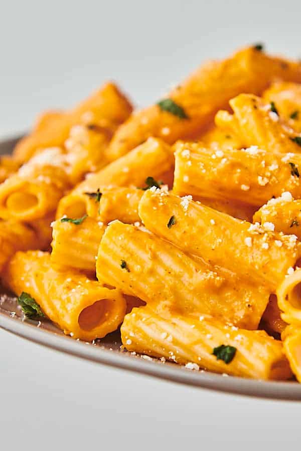 holding a plate of pasta with creamy vodka sauce