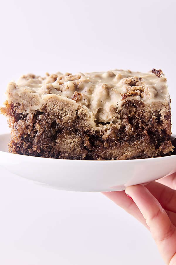 holding a plate with a slice of brown butter banana cake