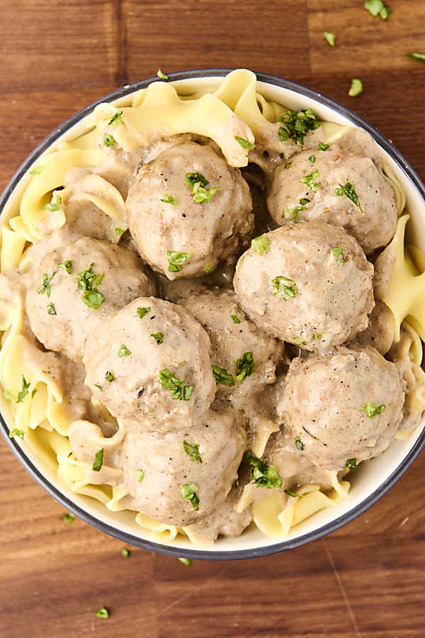 a bowl of crockpot swedish meatballs on top of egg noodles