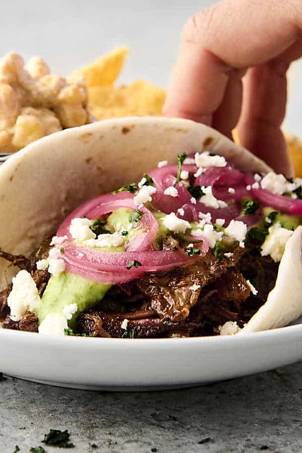 chuck roast taco with flour tortilla, pickled onions, and avocado sauce