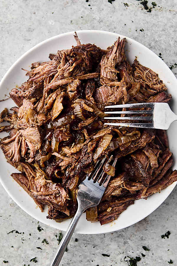 shredded chuck roast on a plate with two forks
