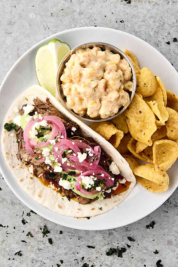plate with chuck roast taco, fritos, and corn dip