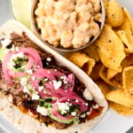 crockpot chuck roast tacos on a plate with corn dip and fritos