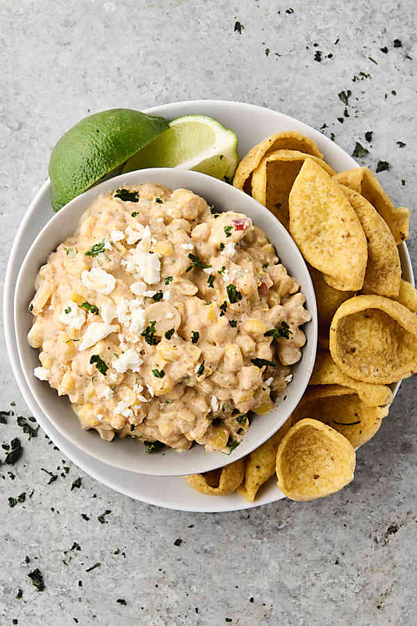 Mexican street corn dip in a bowl on a plate with fritos