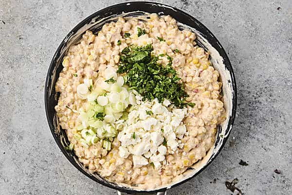 stirring cilantro, green onions, and feta into the corn dip