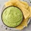 avocado dip in a bowl with chips on the side