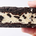 holding an oreo ice cream sandwich with homemade cookies and cream ice cream