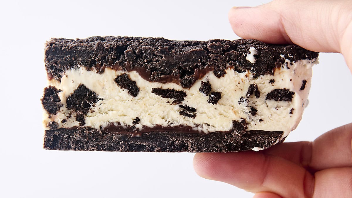 holding an oreo ice cream sandwich with homemade cookies and cream ice cream