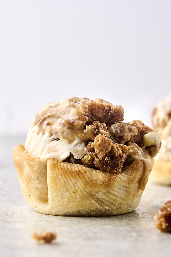 scoop of no churn caramel apple ice cream with graham cracker crumble in a pie crust cup