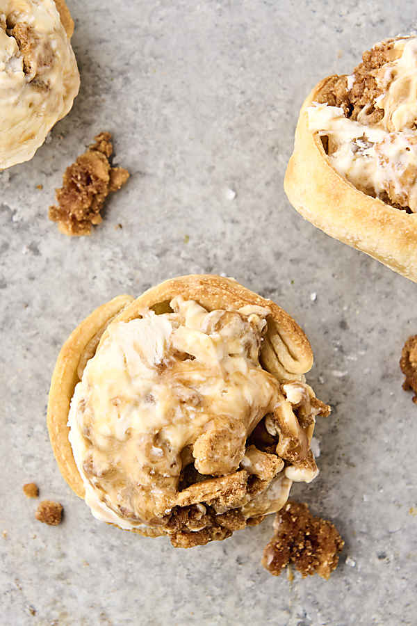 homemade vanilla ice cream with caramel and apple pie filling in a pie crust cup