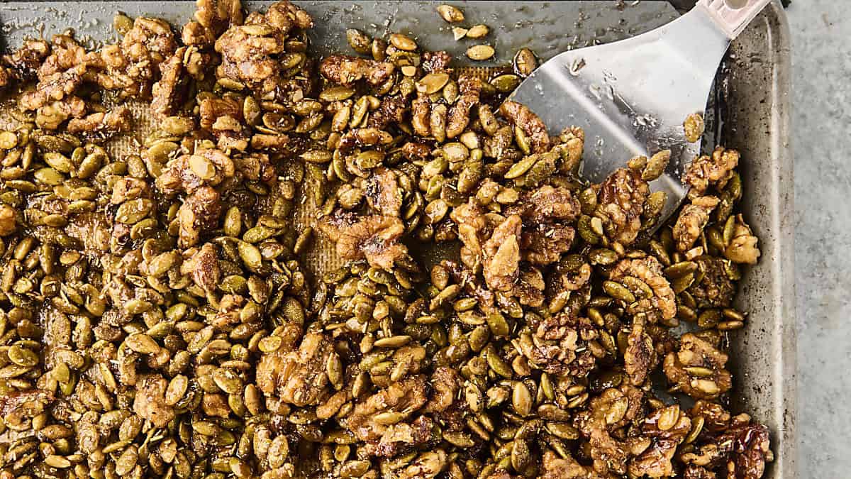 candied rosemary walnuts with pumpkin seeds on a baking sheet